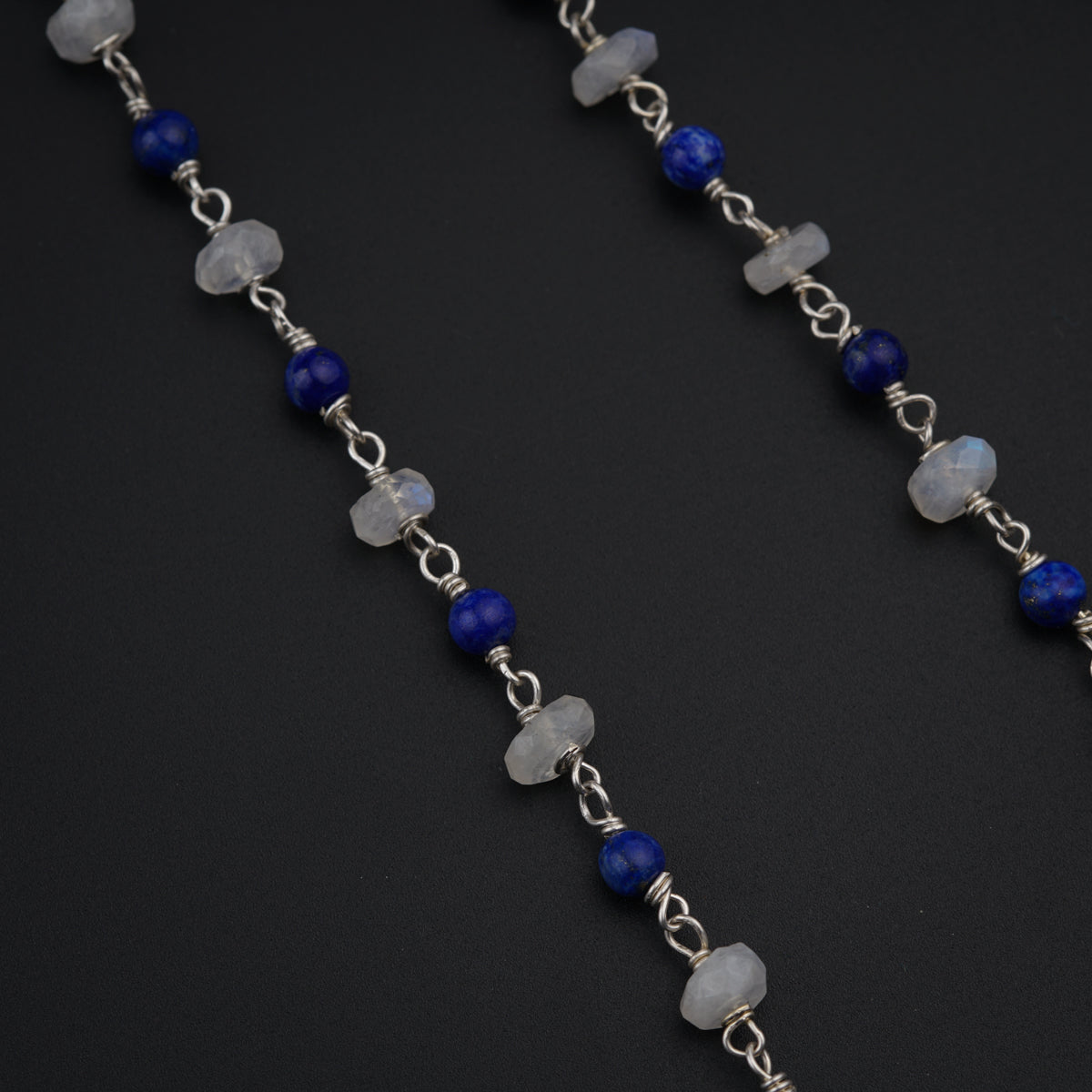 a blue and white beaded necklace on a black surface