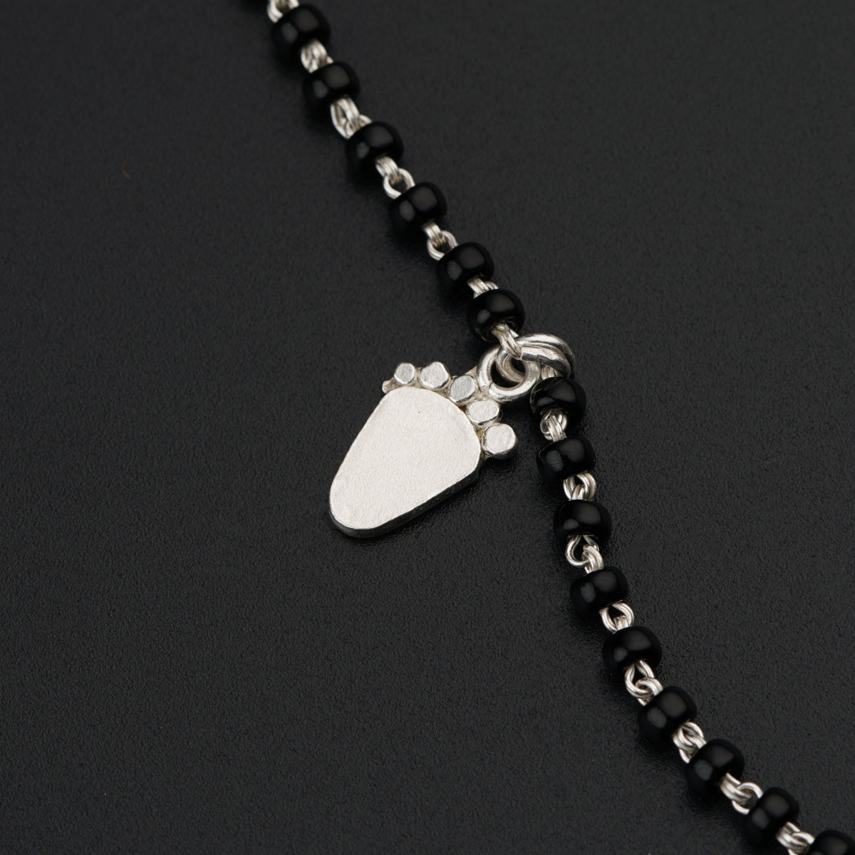 a black beaded necklace with a silver pendant