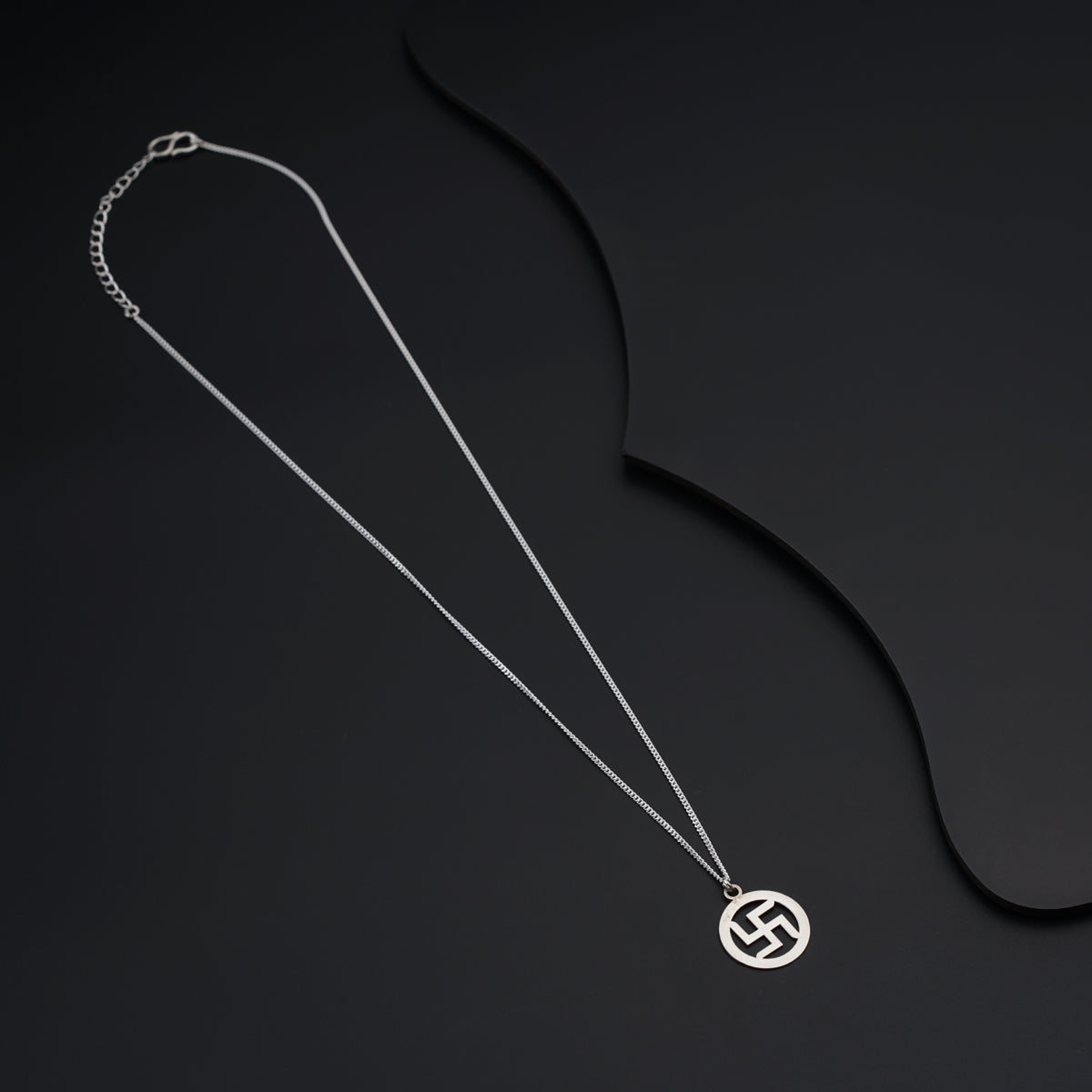 a silver necklace with a circular pendant on a black background