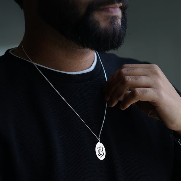 a man wearing a necklace with a monogrammed disc on it