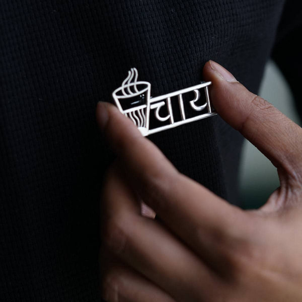 a person holding a pin with a cup of coffee on it