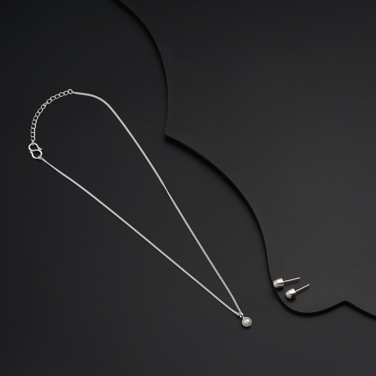 a necklace with a chain and a pendant on a black background