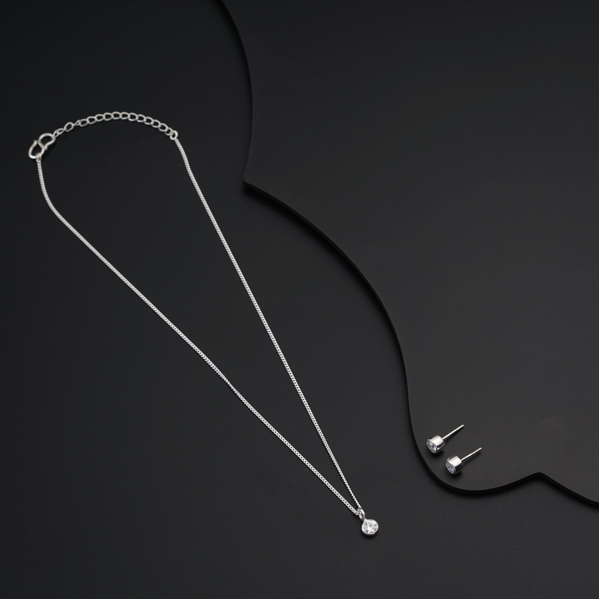 a necklace and earring on a black surface