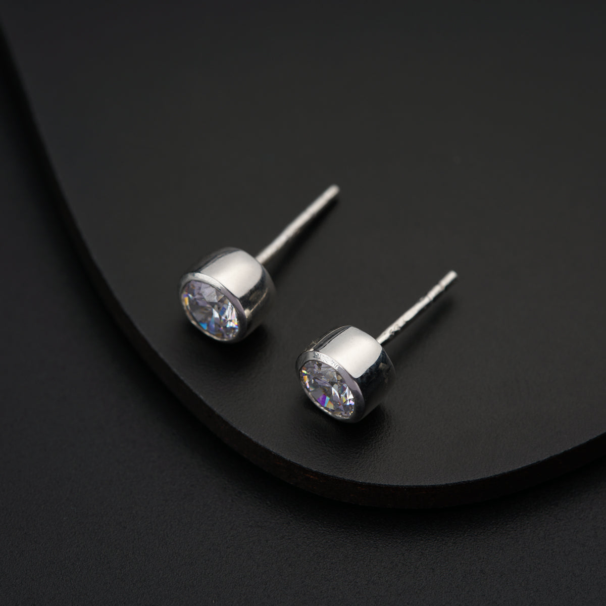 a pair of diamond earrings on a black surface