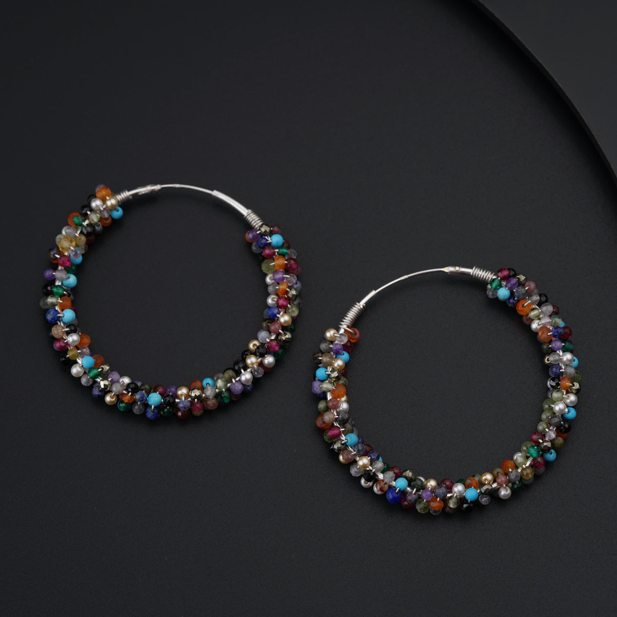 a pair of hoop earrings with multi colored beads