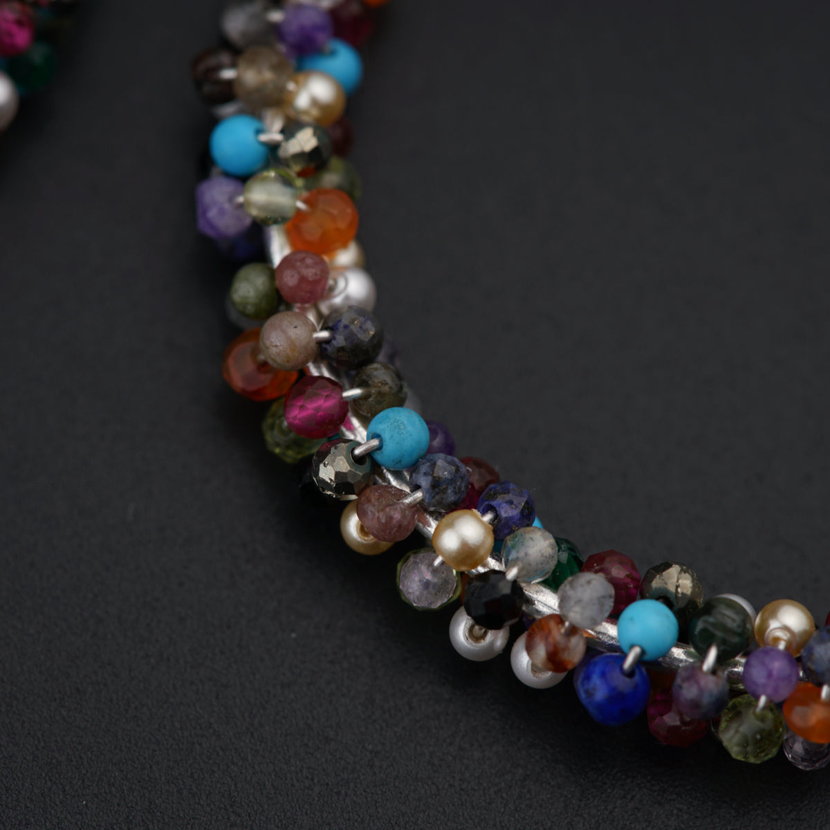 a multicolored beaded necklace on a black surface