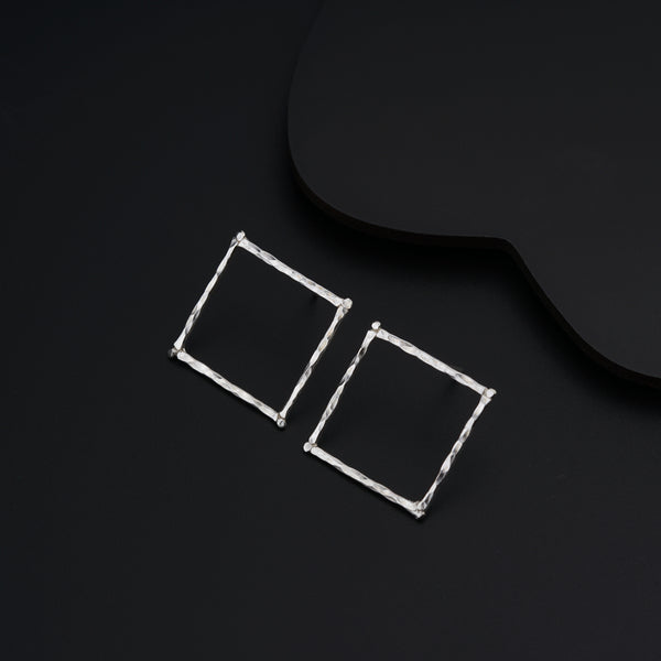 a pair of square earrings sitting on top of a black surface
