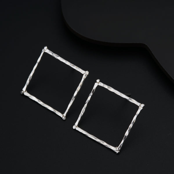 a pair of square earrings sitting on top of a black surface