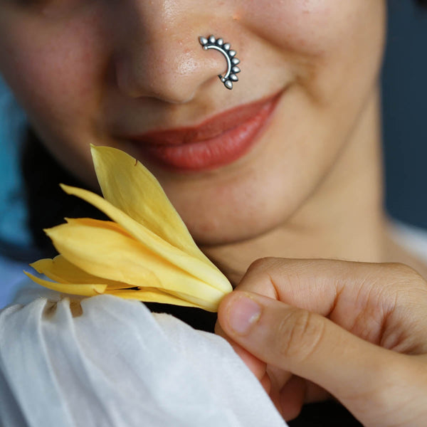 Silver nose pin with floral design on woman's nose