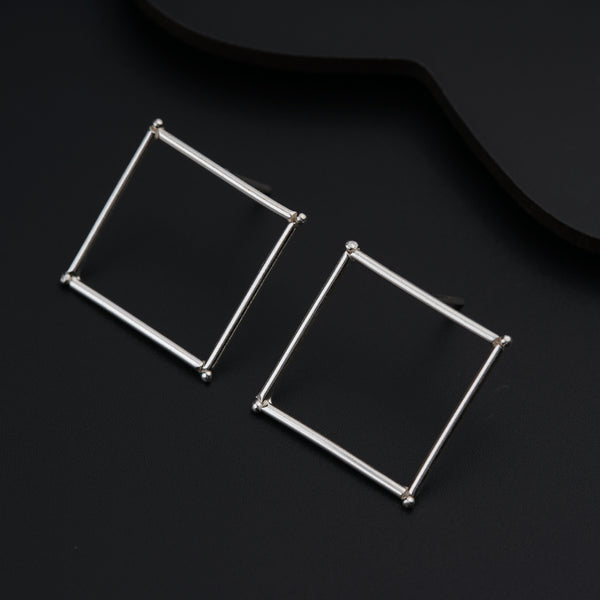 a pair of square earrings sitting on top of a black surface