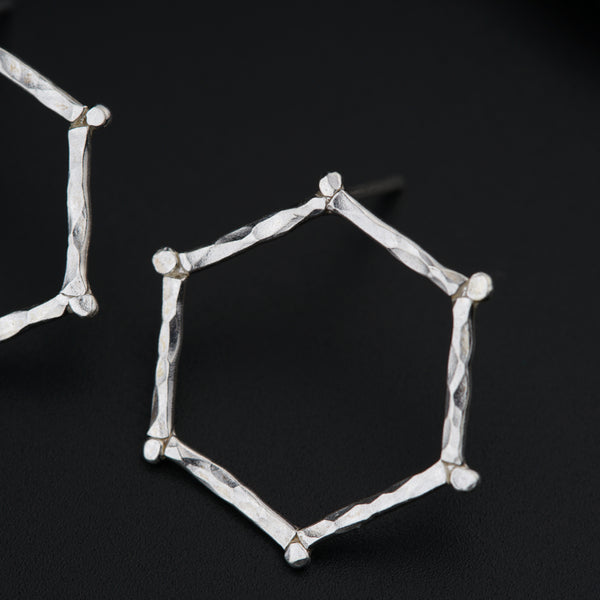 a pair of silver earrings on a black surface