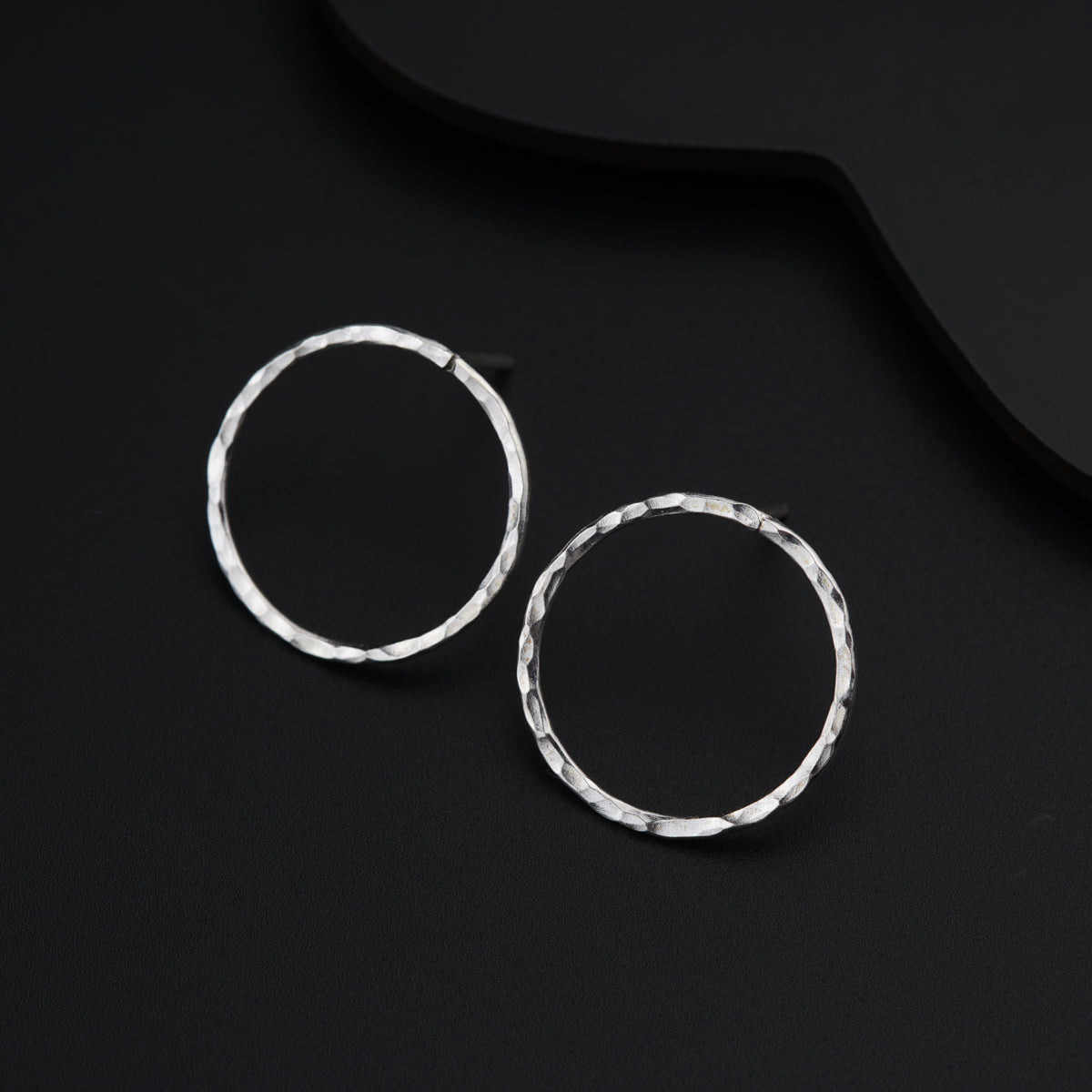 a pair of silver hoop earrings on a black background