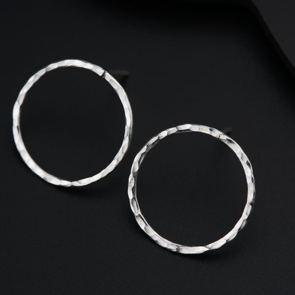 a pair of silver hoop earrings on a black surface