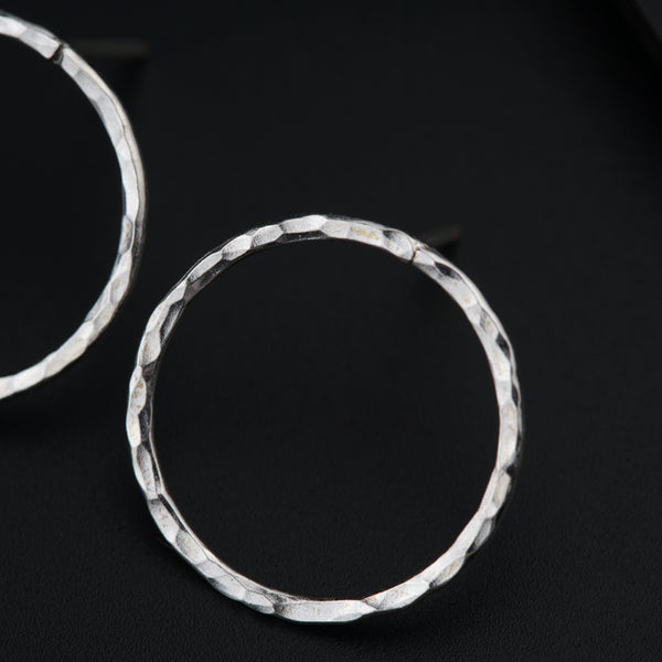 a pair of silver hoop earrings on a black surface