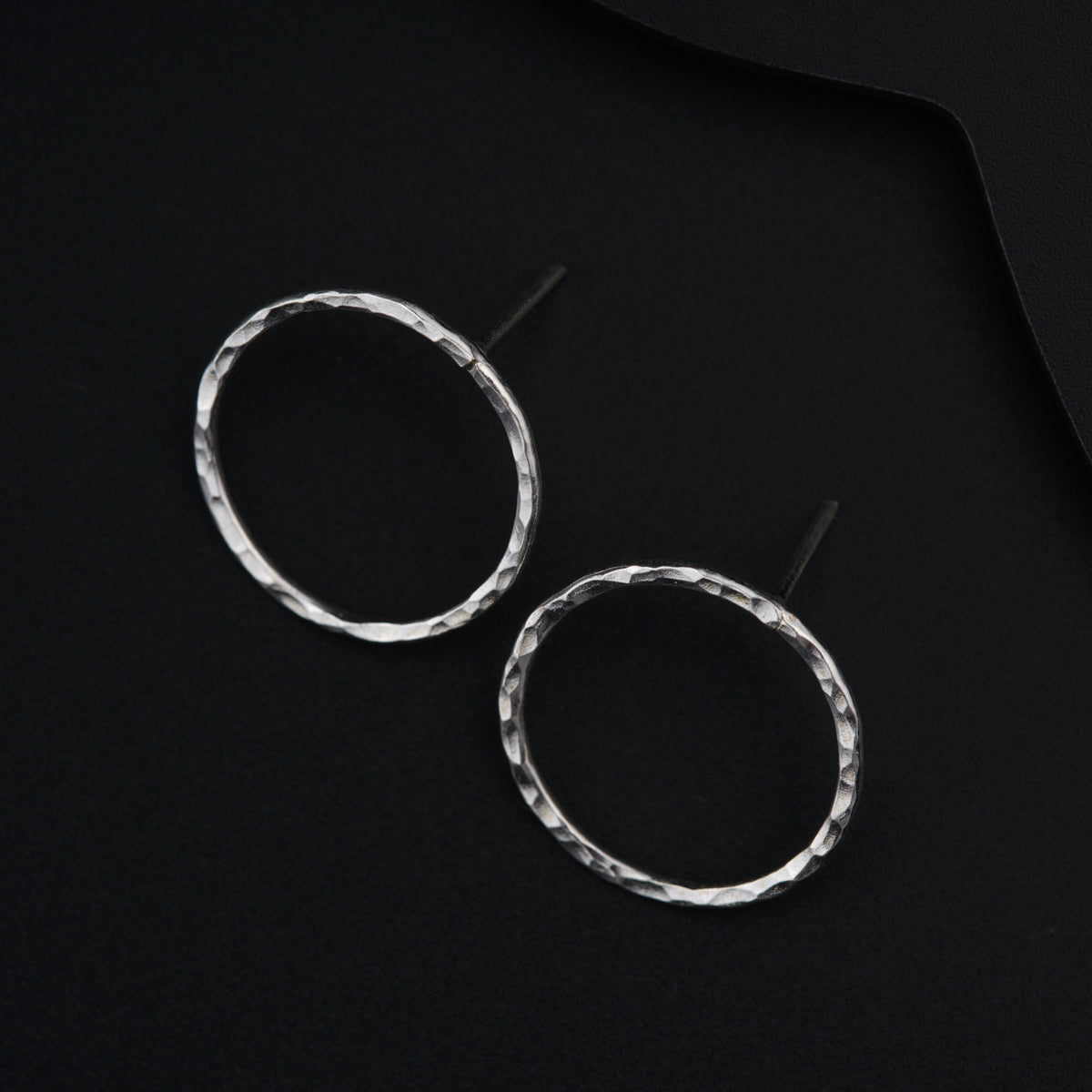 a pair of silver hoop earrings on a black background