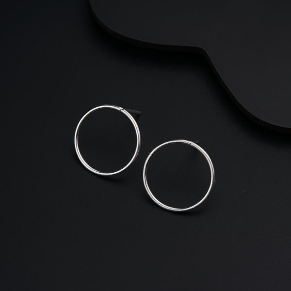 a pair of silver hoop earrings on a black background