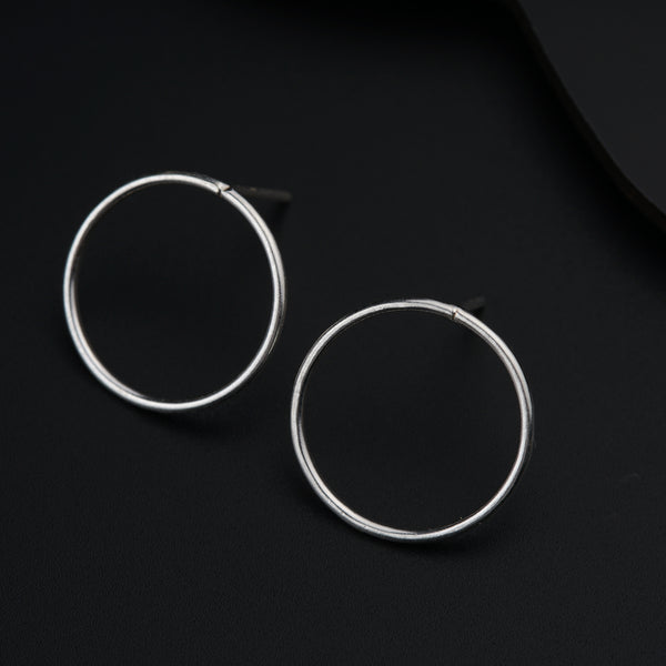 a pair of silver hoop earrings on a black surface