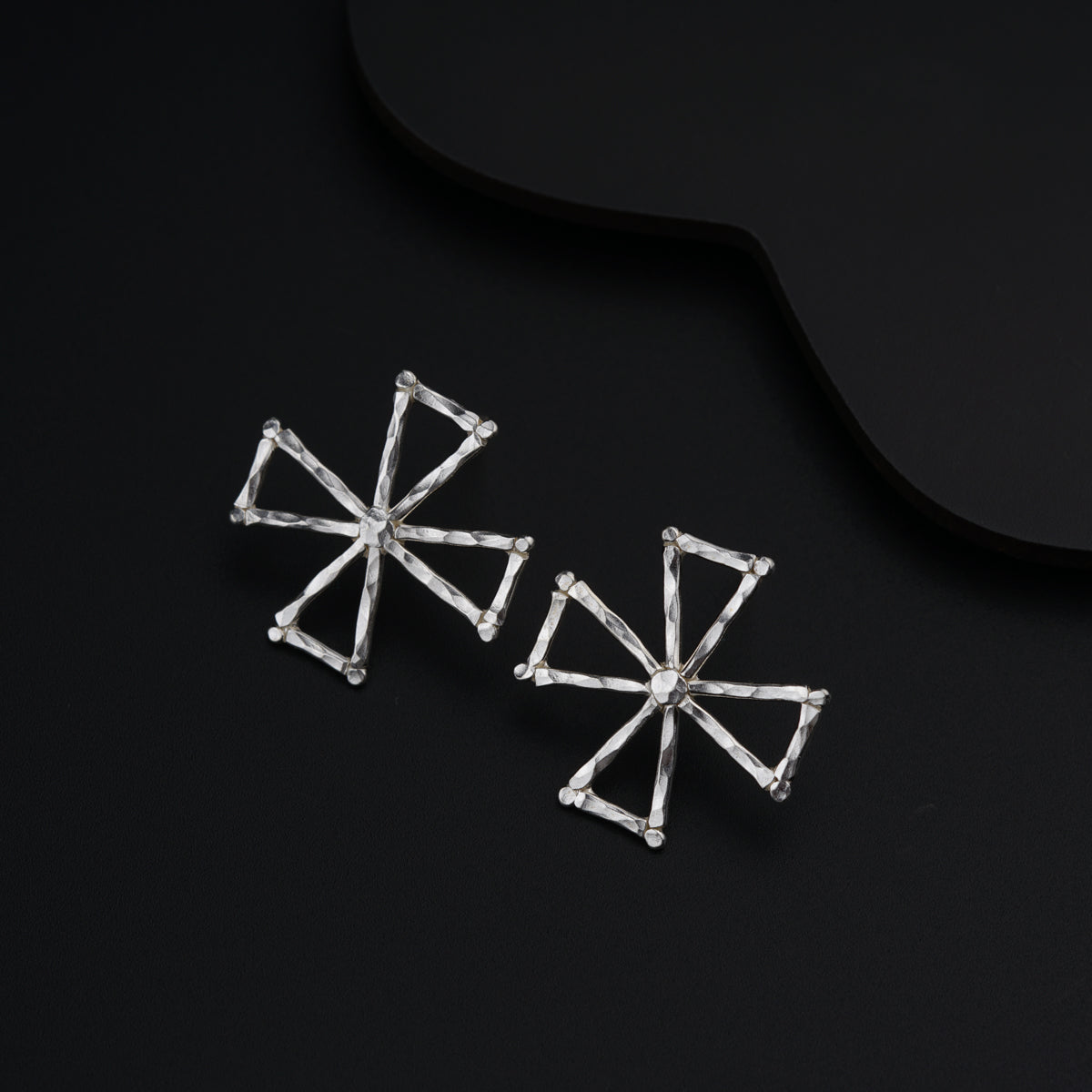 a pair of earrings sitting on top of a black surface