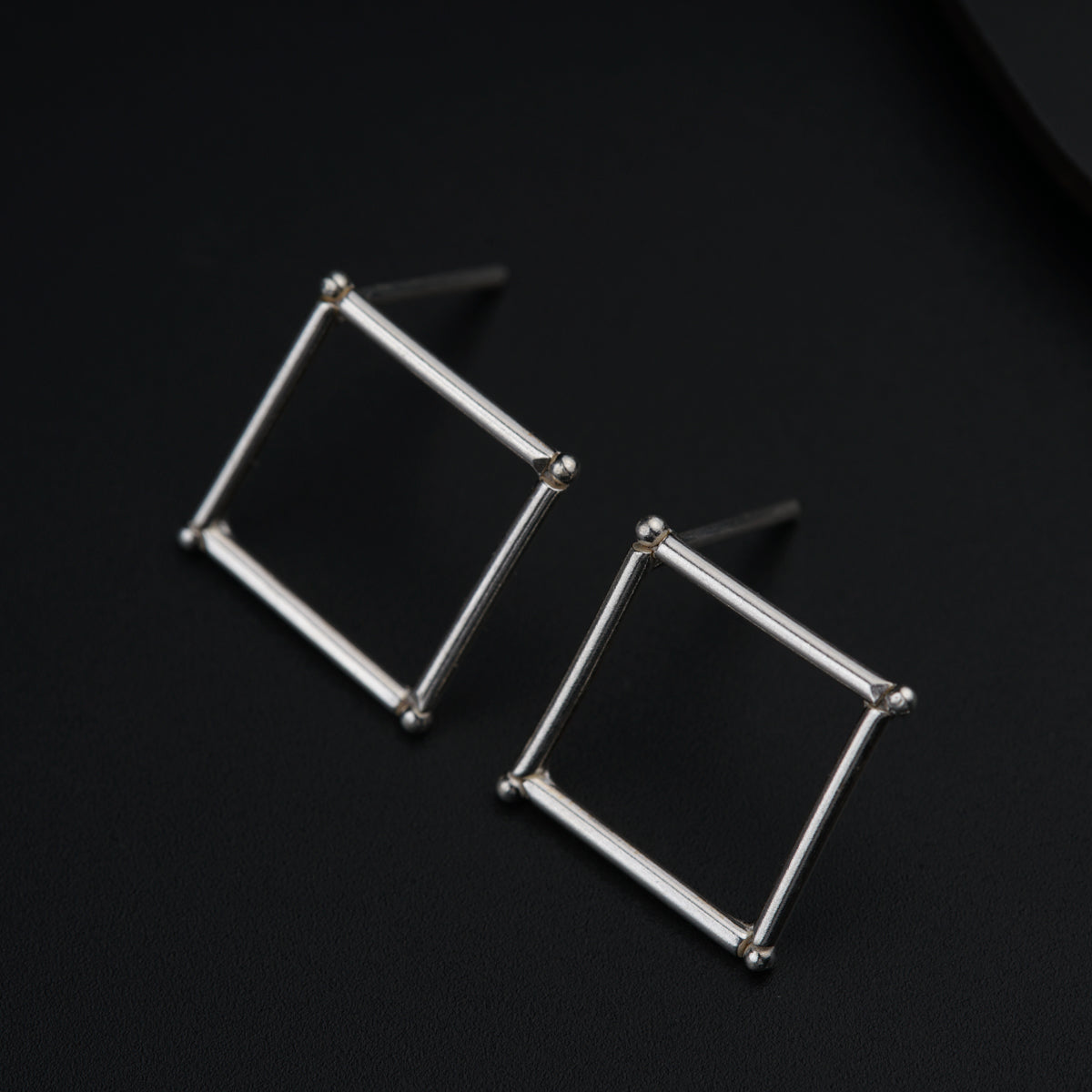 a pair of square earrings on a black surface