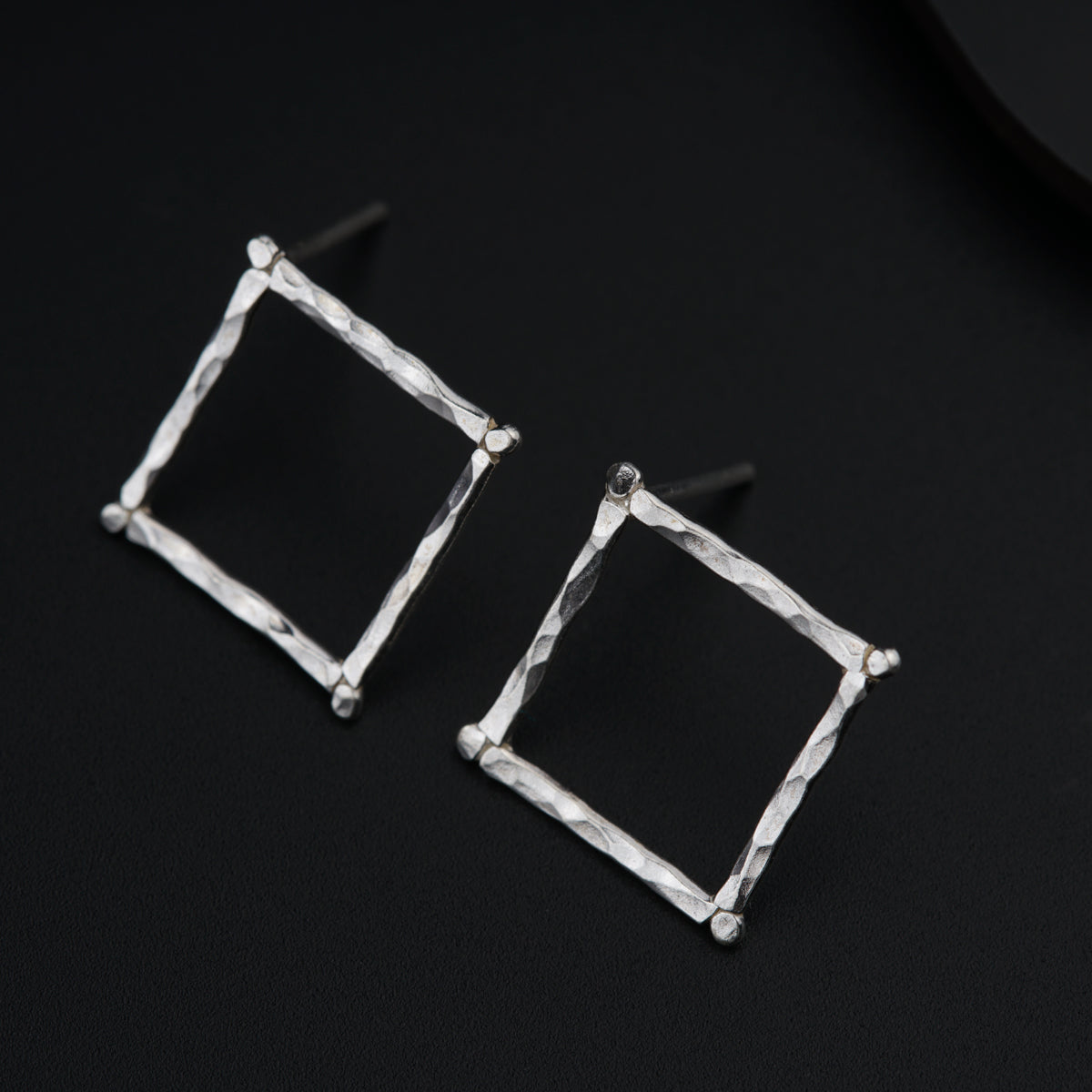 a pair of square shaped earrings on a black surface