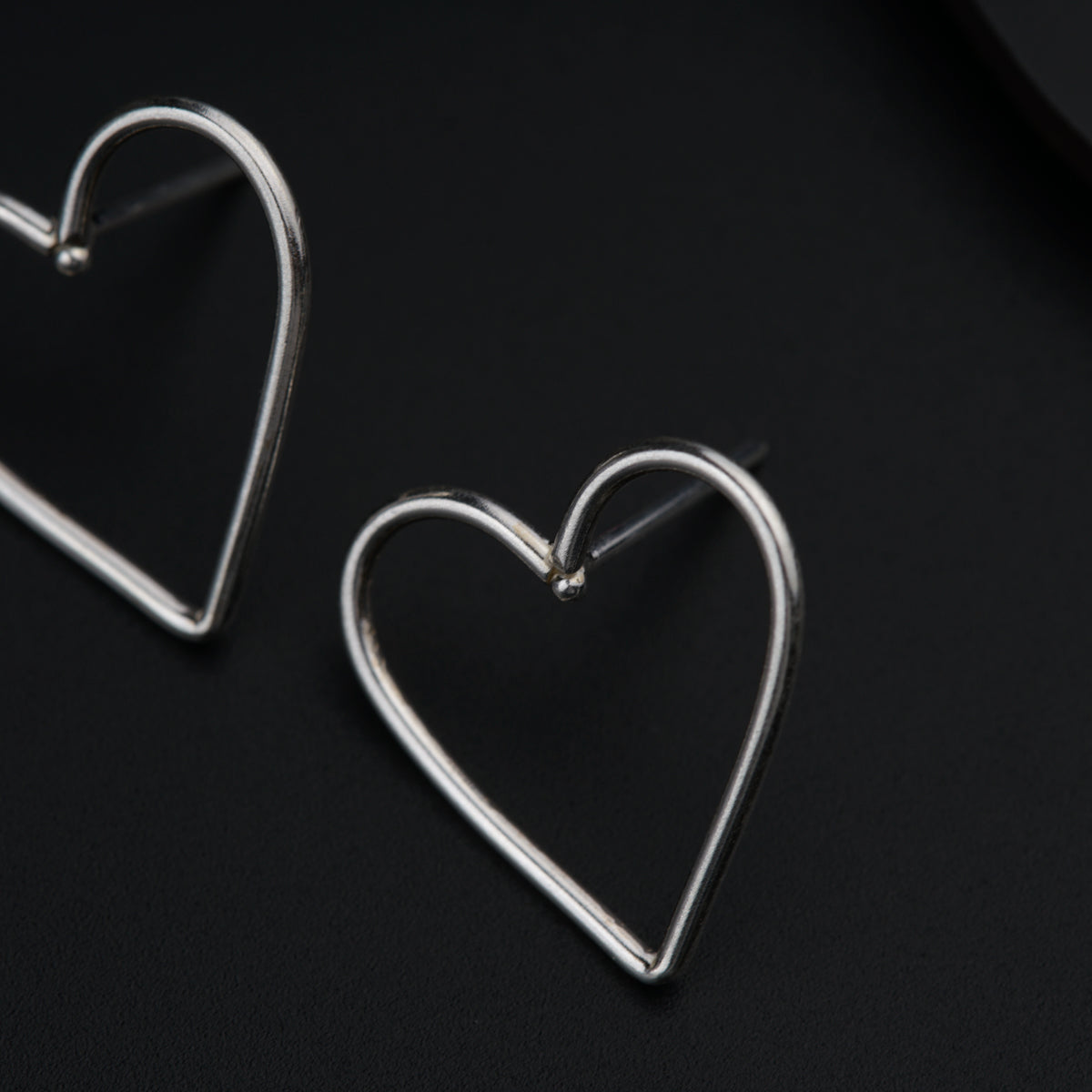 a pair of heart shaped earrings on a black surface
