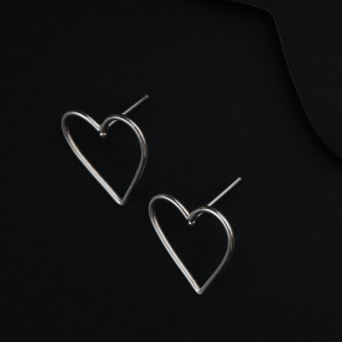 a pair of heart shaped earrings on a black background