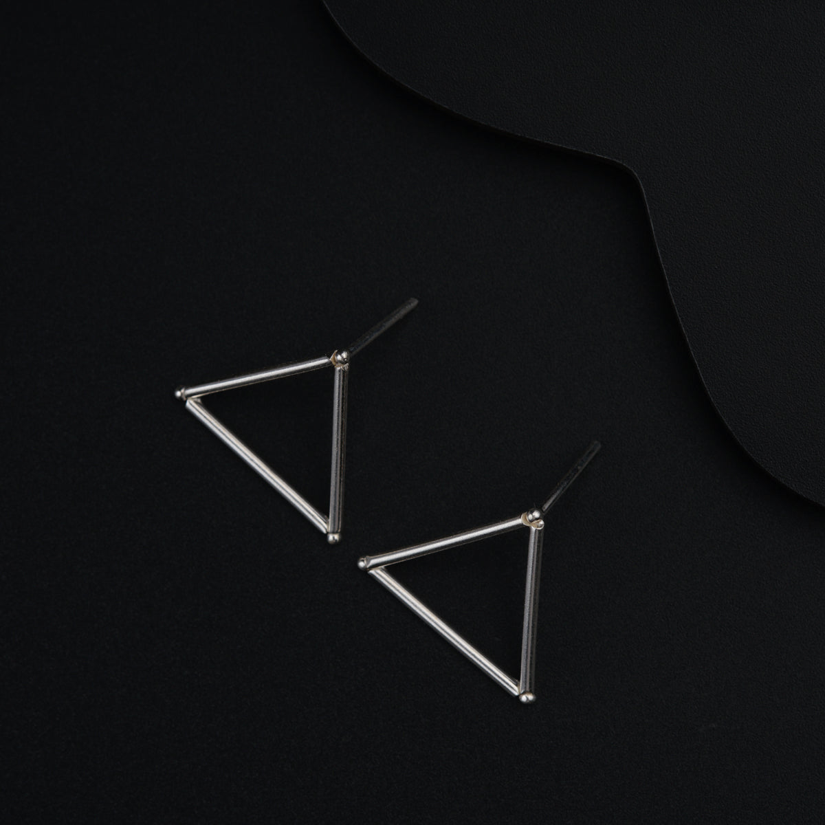 a pair of triangle earrings on a black background