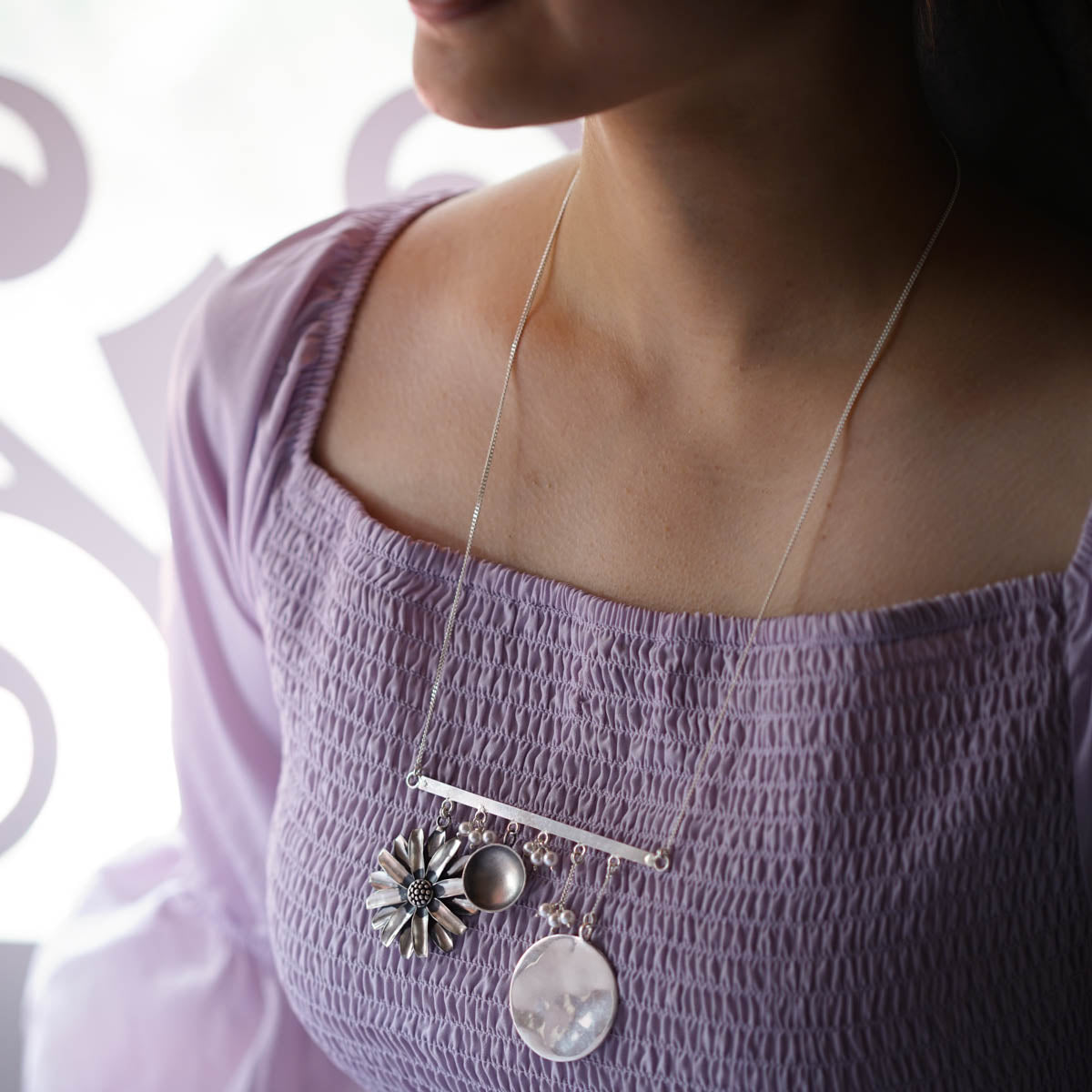 a woman wearing a purple top and a silver necklace