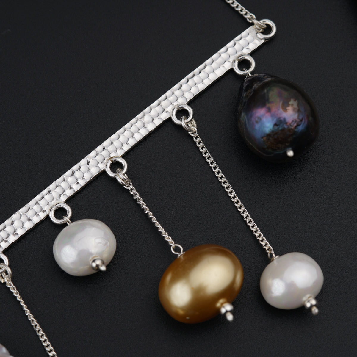 a close up of three different necklaces on a black surface
