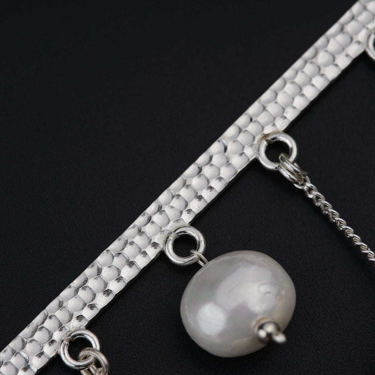 a close up of a necklace with a pearl on it