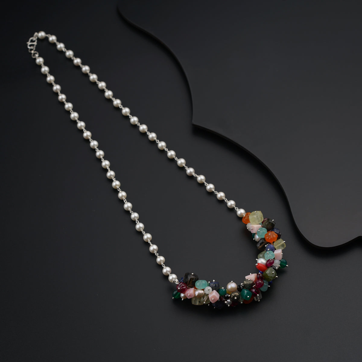 a necklace with pearls and beads on a black surface