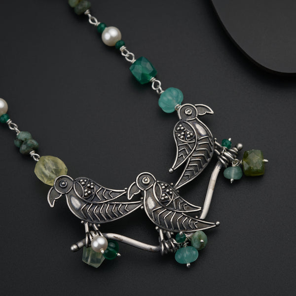 a necklace with green beads and a bird on it