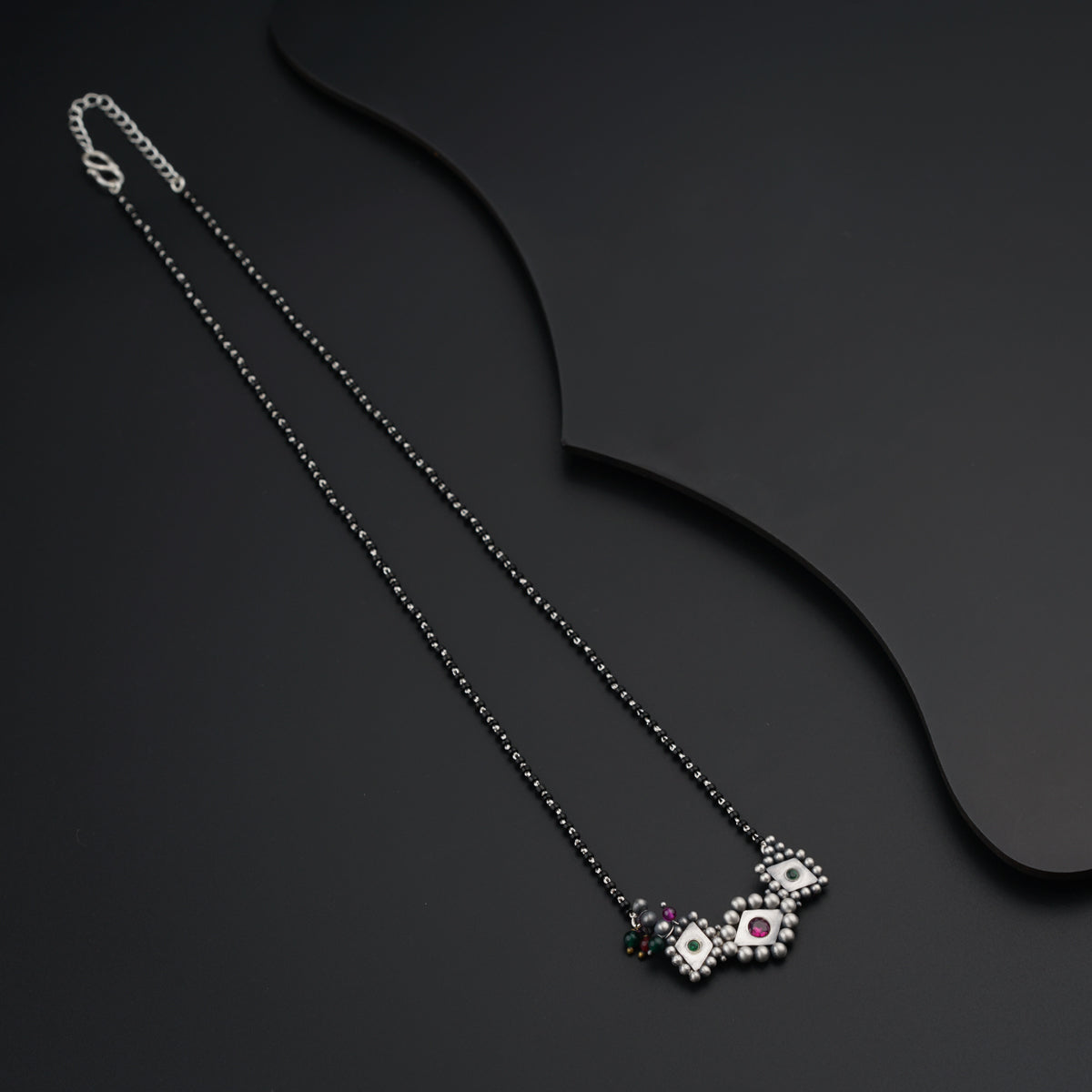a black necklace with a white and pink flower on it