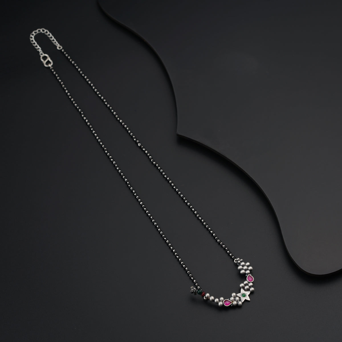 a black necklace with a silver chain and pink stones