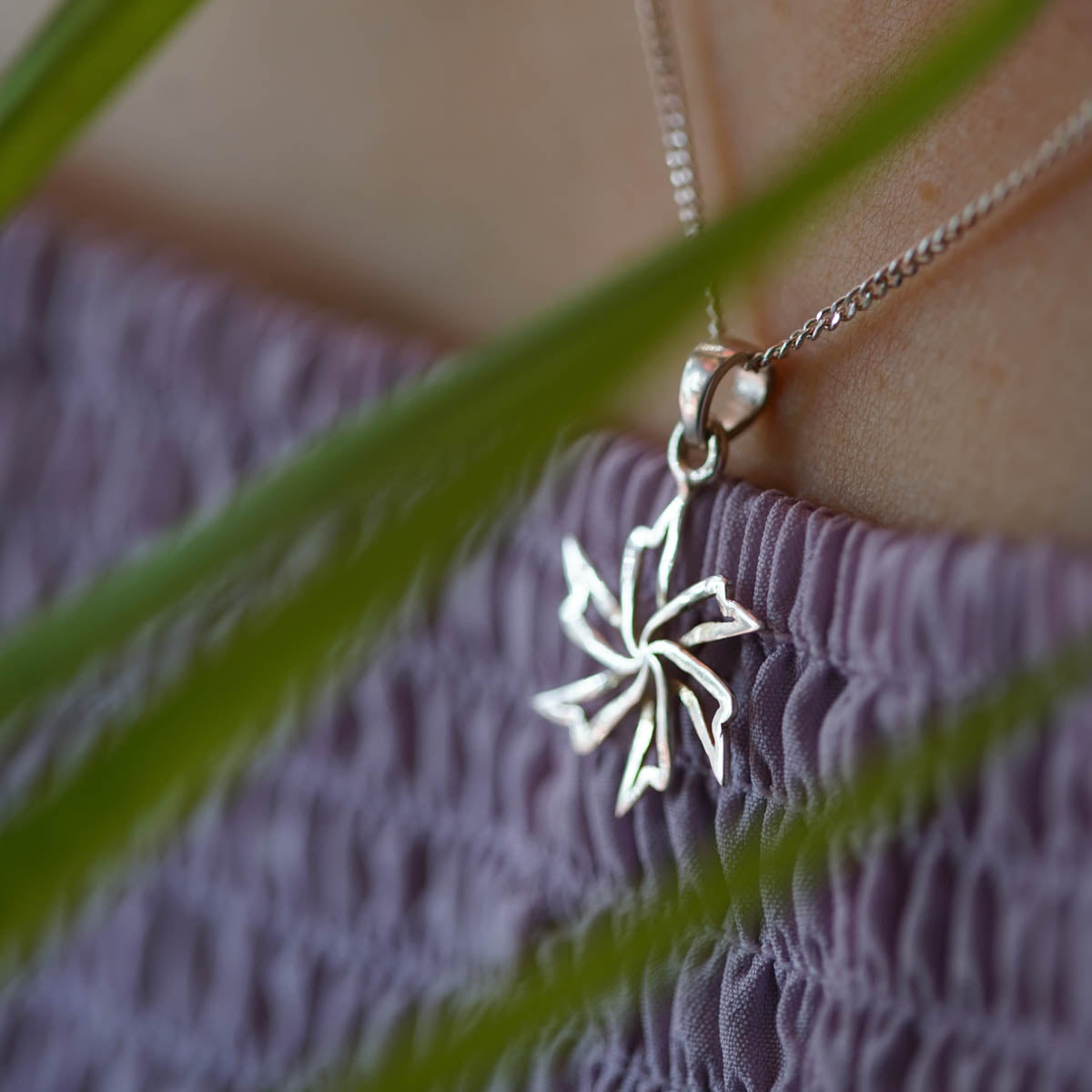 a close up of a person wearing a necklace with a flower on it