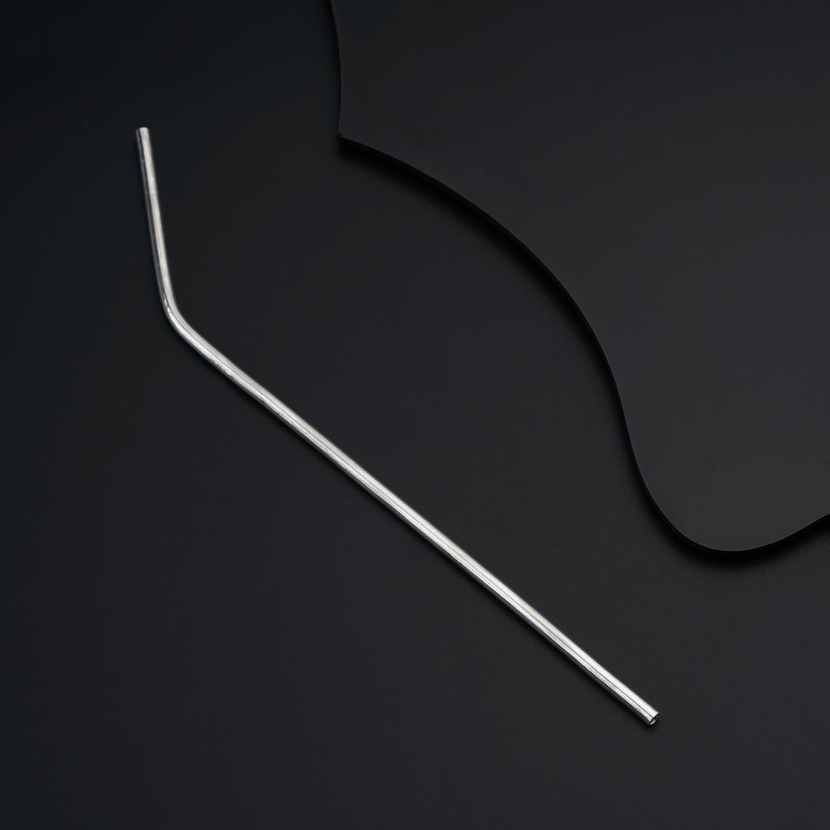 a pair of metal straws sitting on top of a black surface
