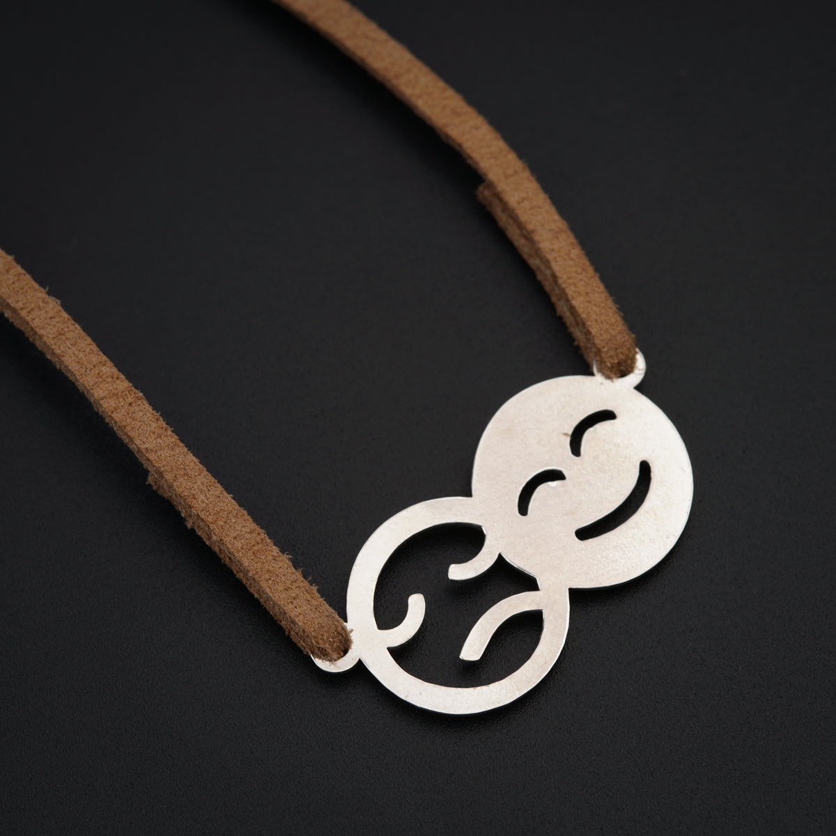 a necklace with a smiley face on a brown cord