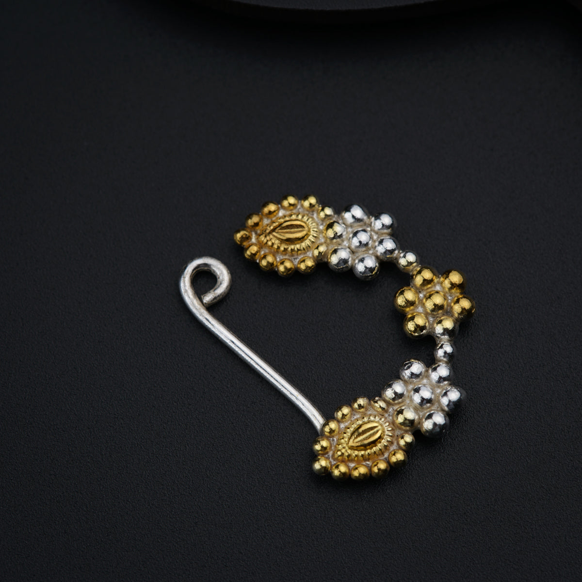 a pair of gold and silver earrings on a black surface