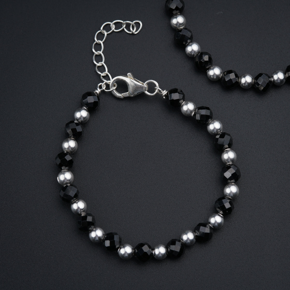 a black and silver beaded bracelet on a black surface