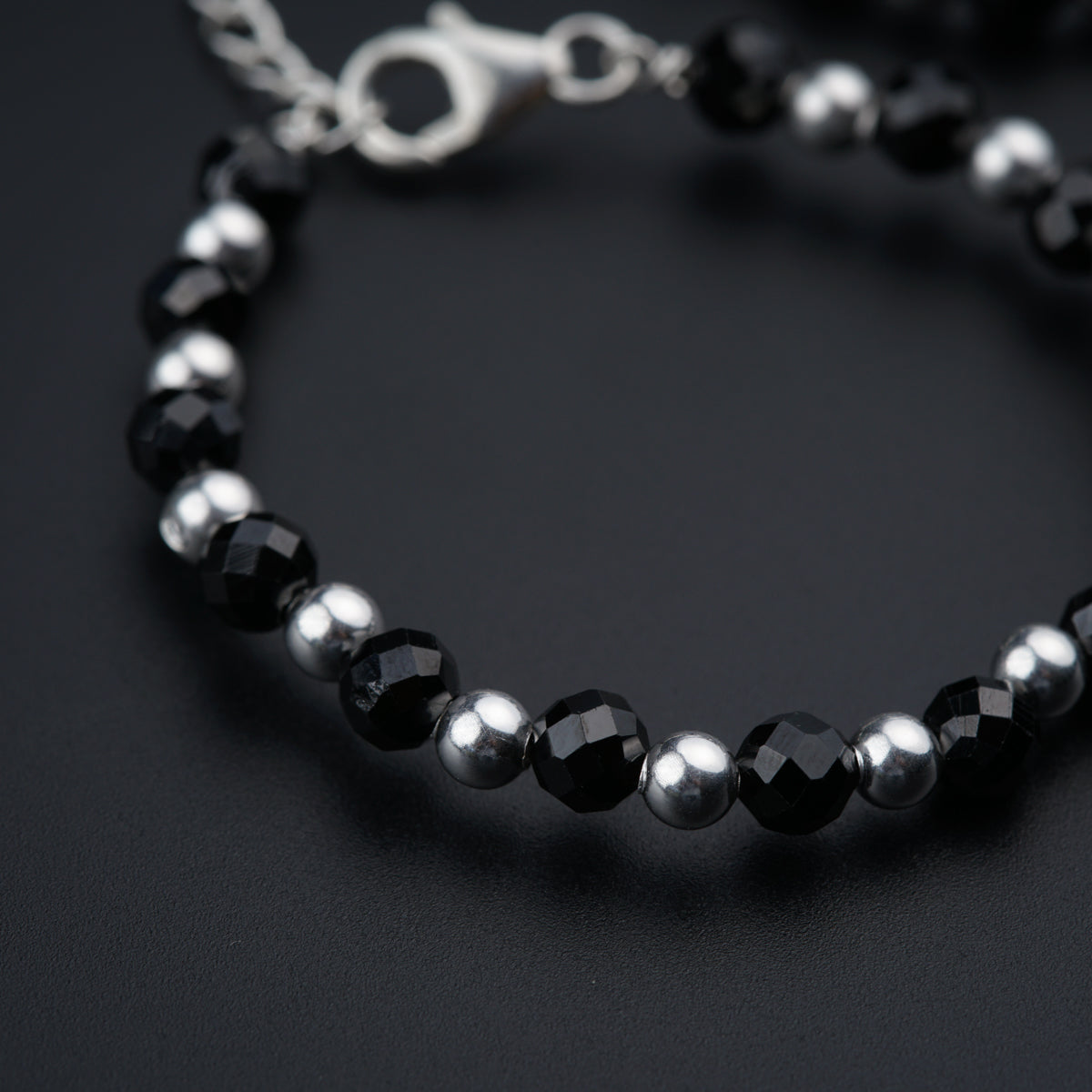 a black and silver beaded bracelet on a black surface