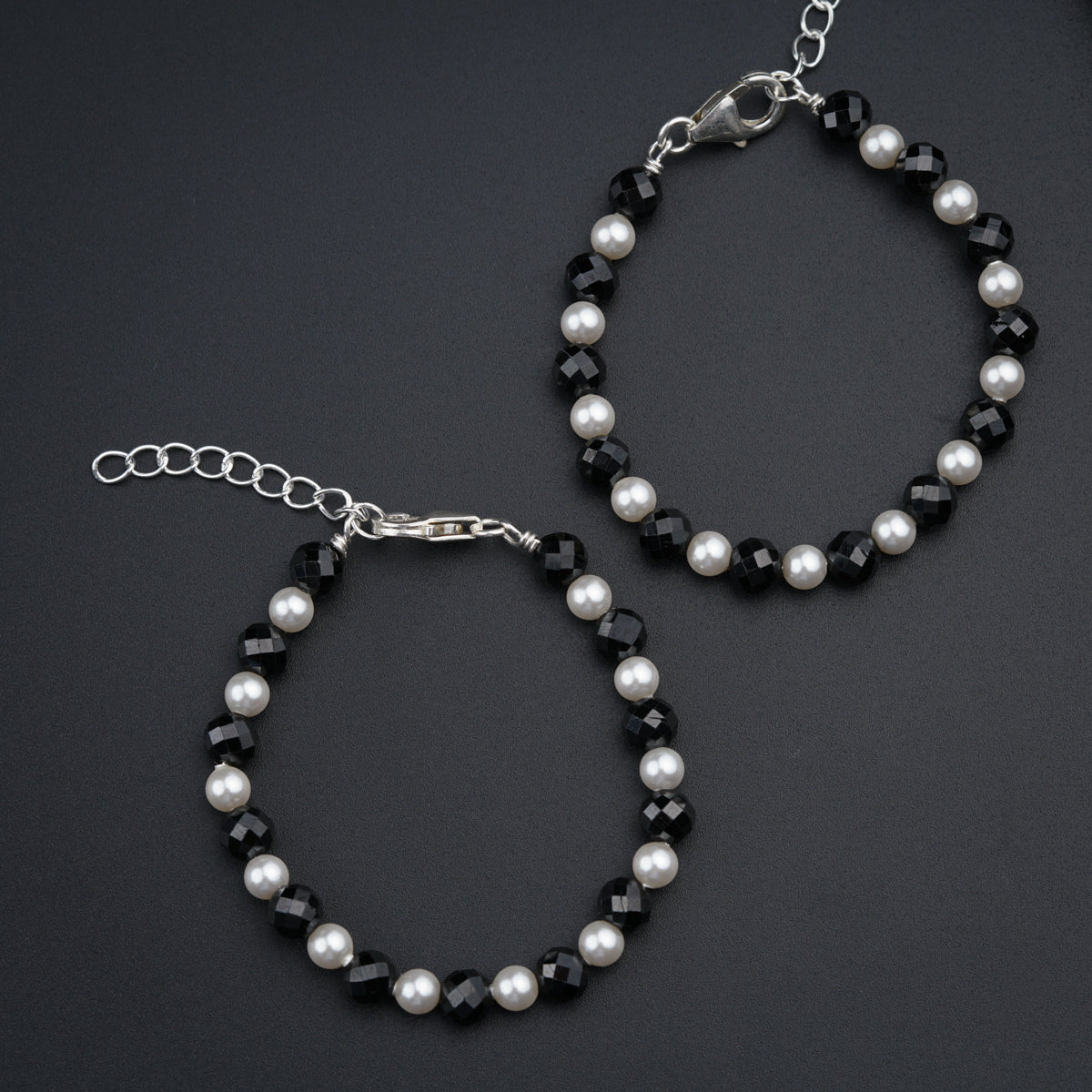 a pair of bracelets with pearls and black beads