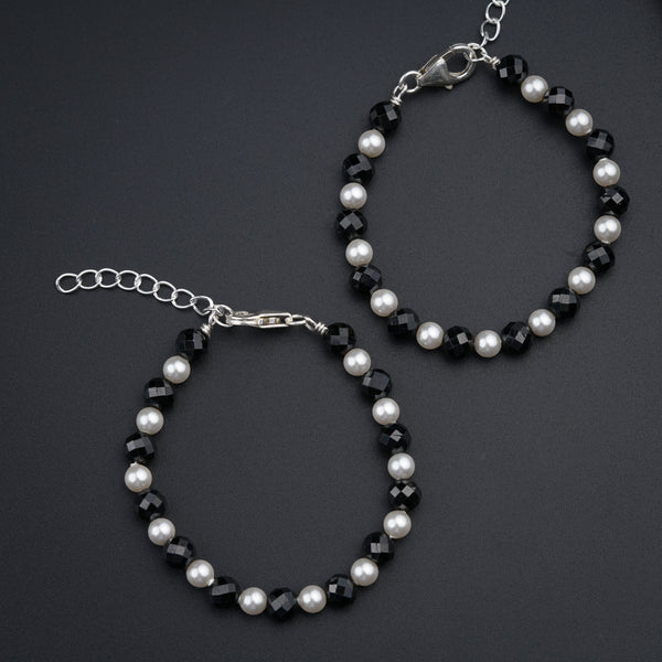 a pair of bracelets with pearls and black beads