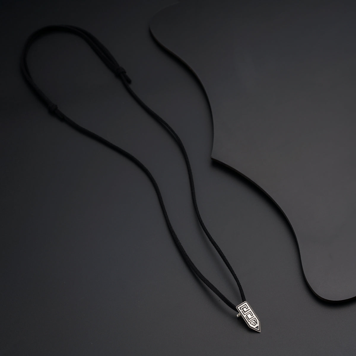 a black cord with a silver pendant on it