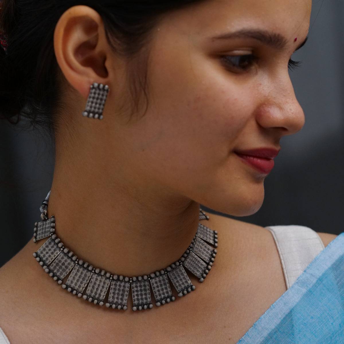 a close up of a woman wearing a necklace and earrings