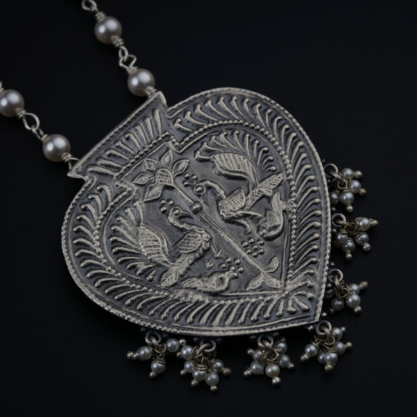 a silver necklace with a bird on it
