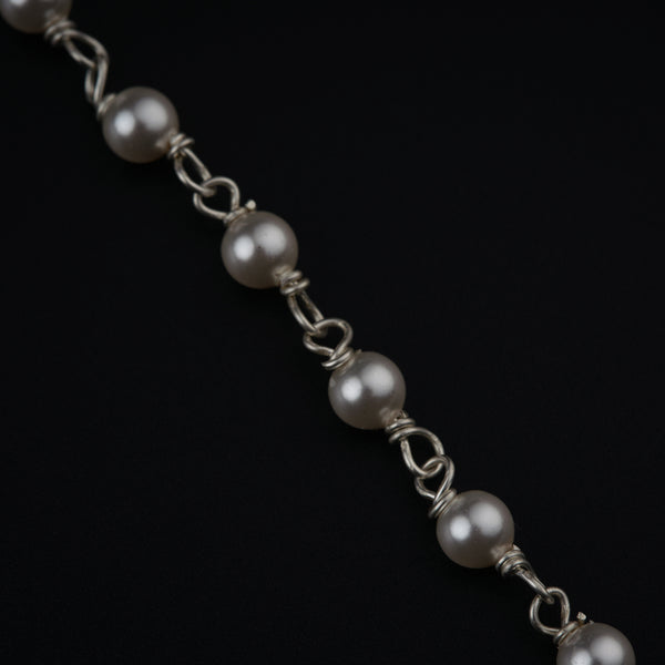 a close up of a chain with pearls on it
