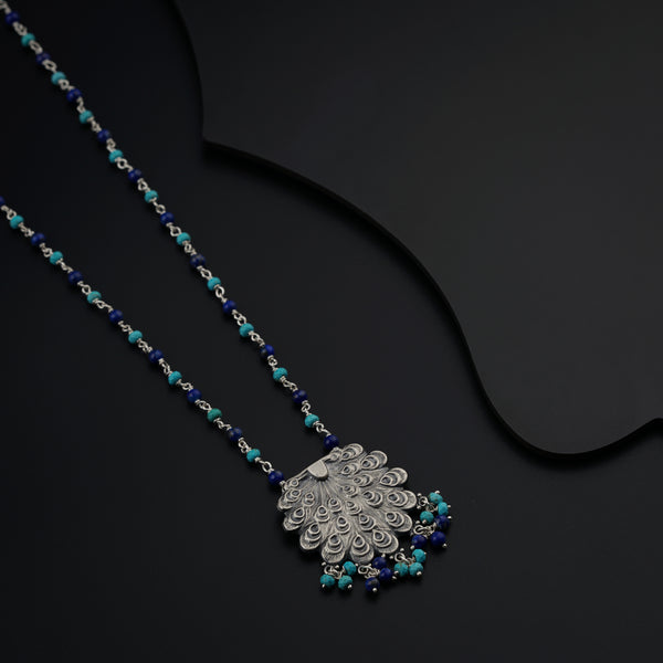 a necklace with a peacock pendant on a black background