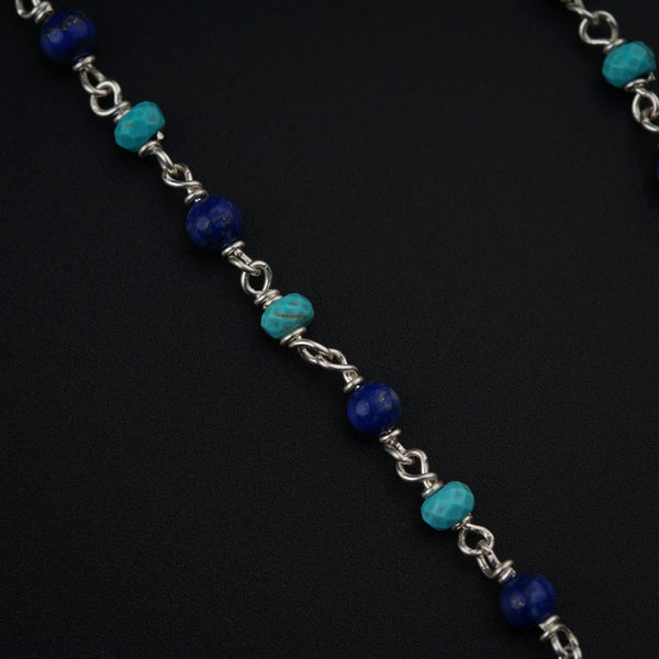 a silver chain with a blue bead on it