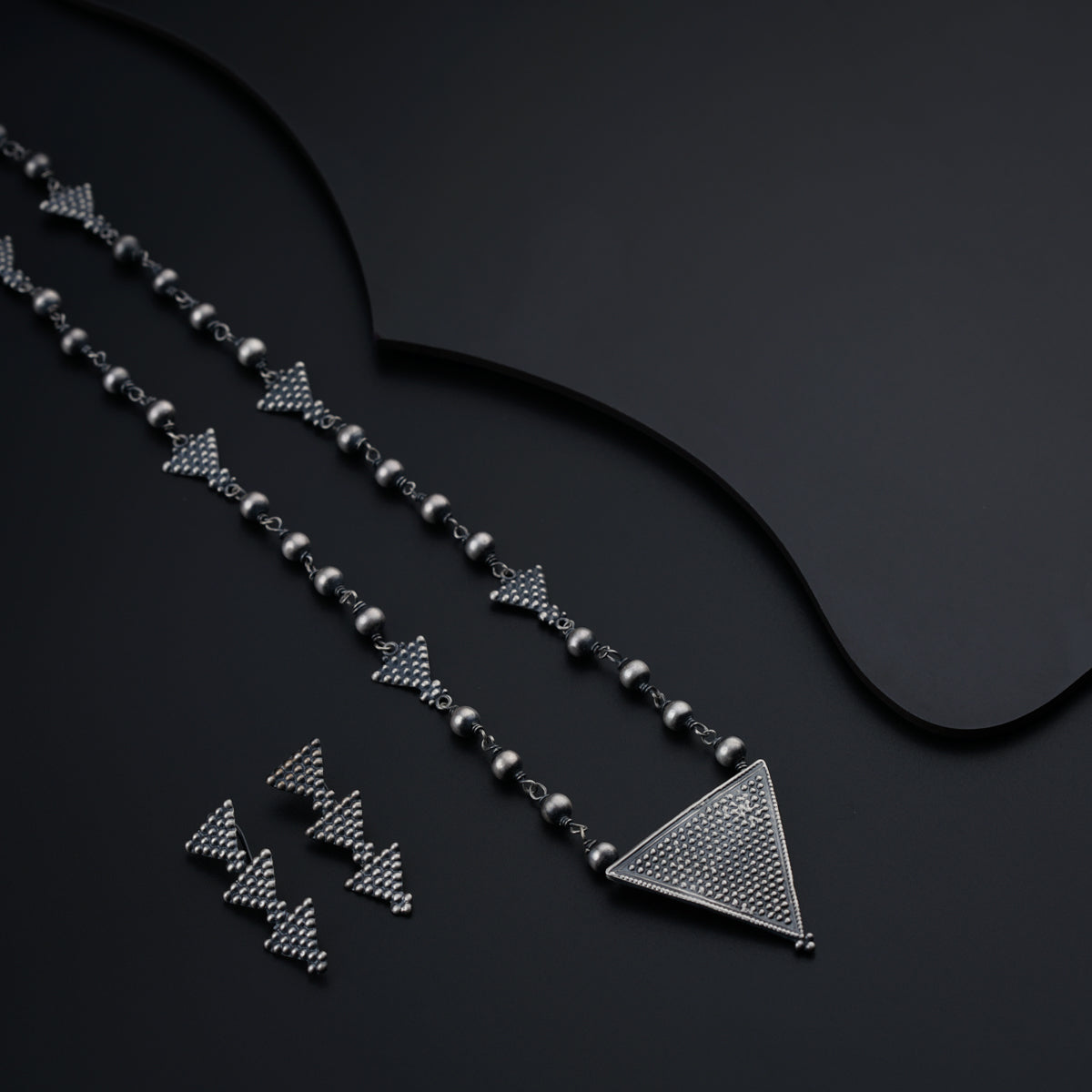 a black background with a chain of silver beads