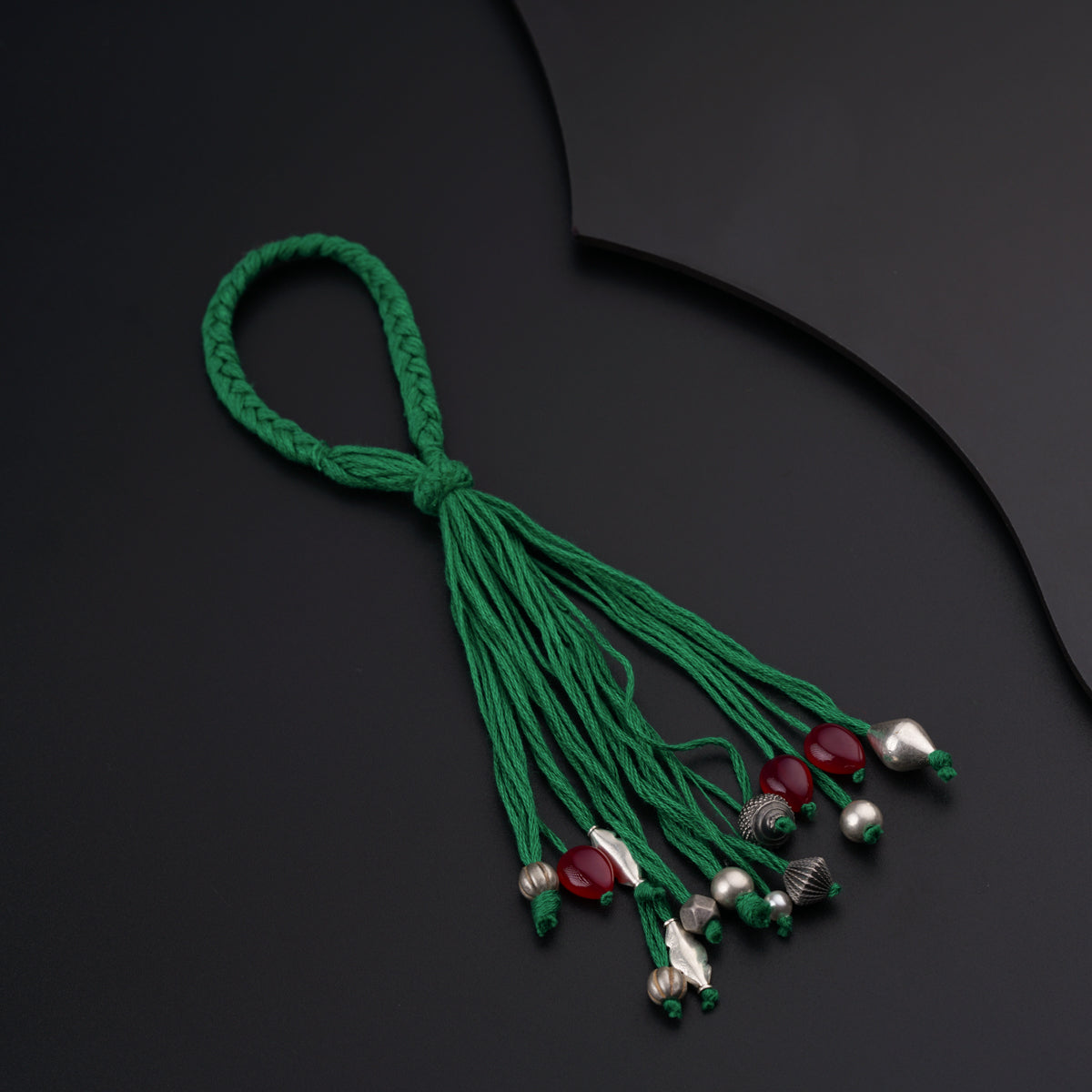 a green string with bells and beads on a black surface